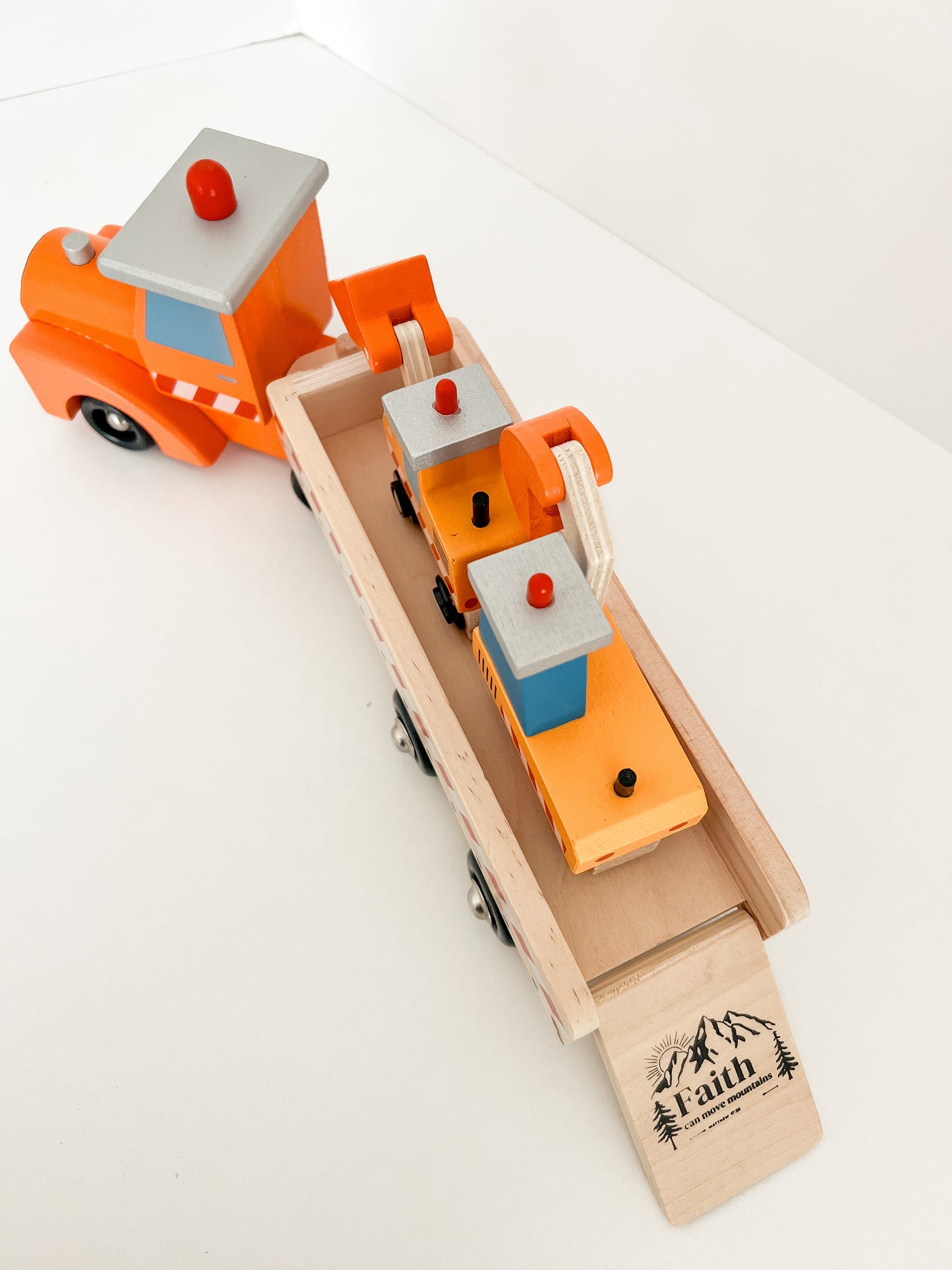 wooden toy construction trucks with the words faith can move mountains printed on the ramp.