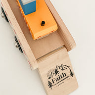 the words "faith can move mountains" printed on a wooden toy truck.