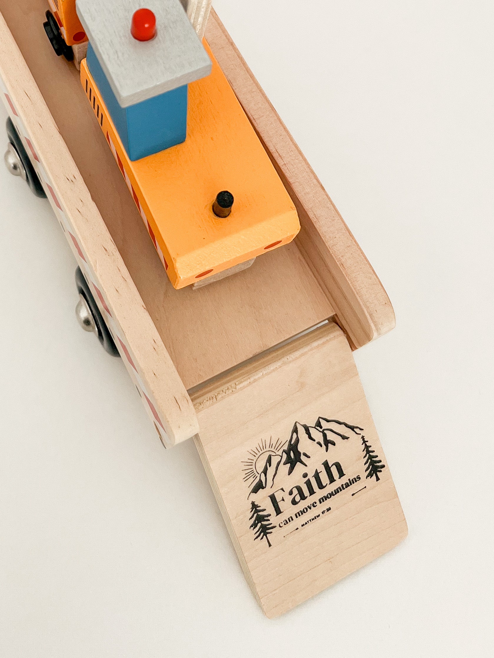 the words "faith can move mountains" printed on a wooden toy truck.