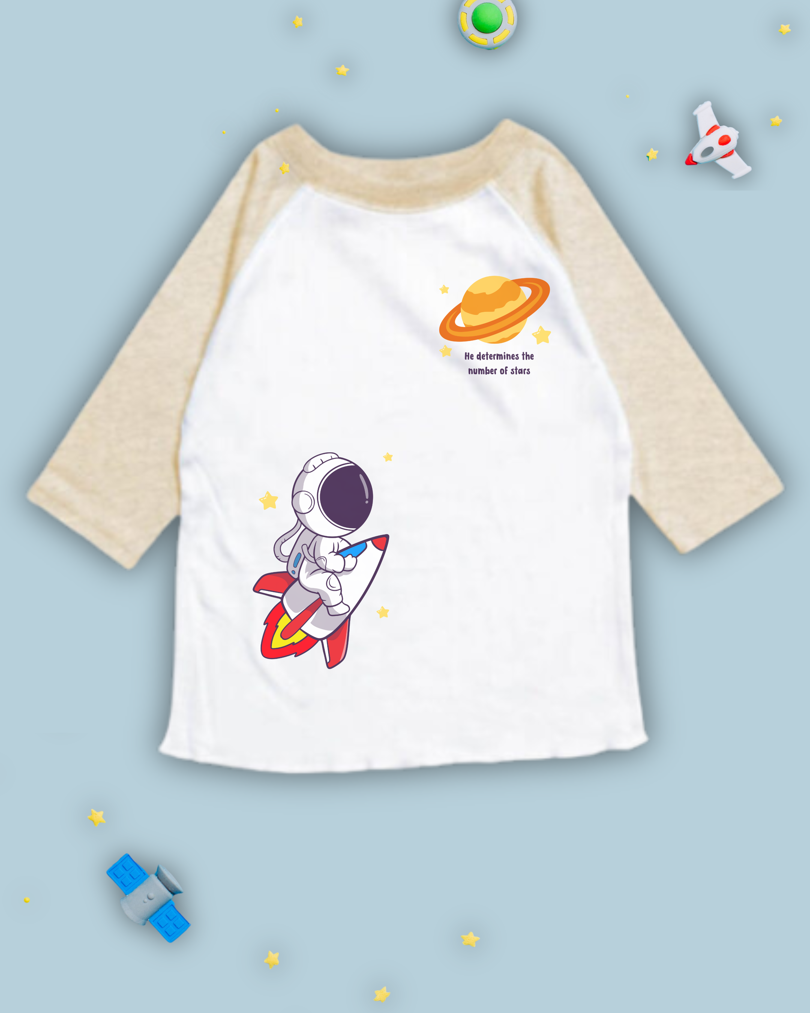 Tan and white raglan tshirt that has an astronaut, rocketship, planet, stars and bible verse from Psalm 147